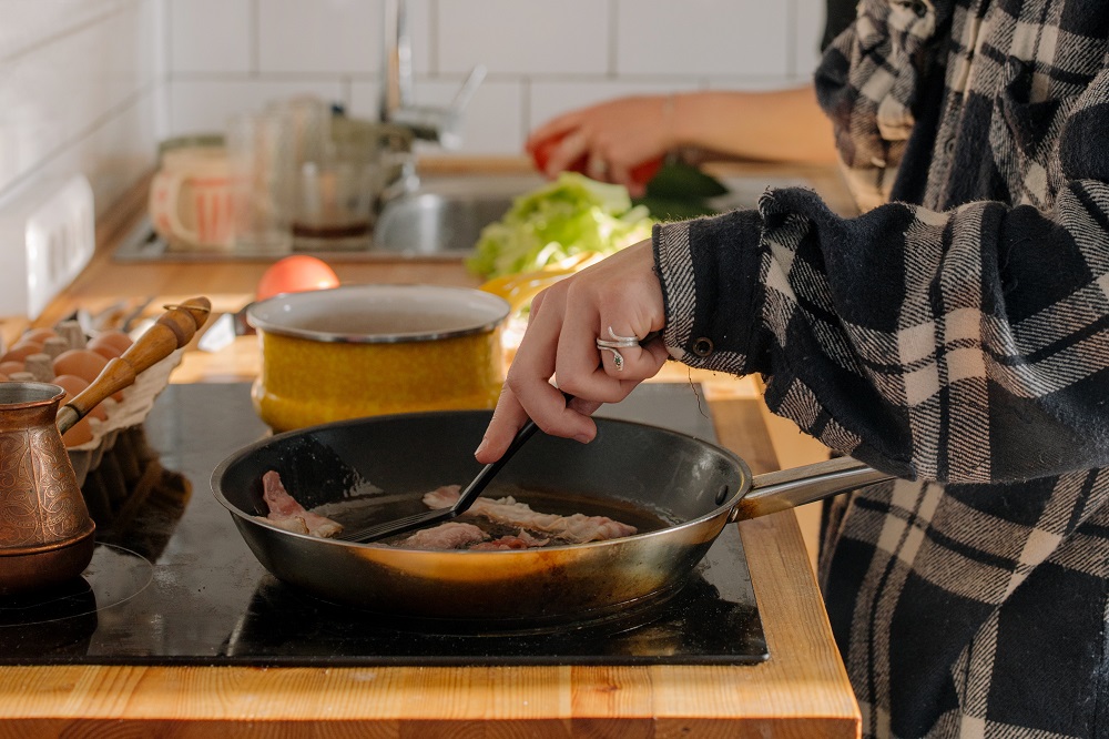 Person making bacon in student apartment at The Green on Campus Drive